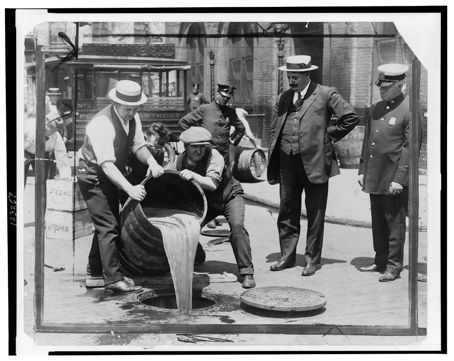 Agents pour a tub of liquor into a sewer during Prohibition.