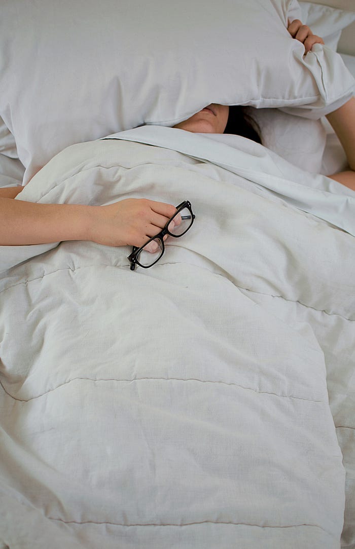 sleeping person holding spectacles in hand.