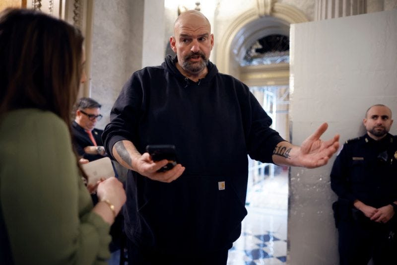 WASHINGTON, DC - FEBRUARY 12: Sen. John Fetterman (D-PA) uses a speech-to-text app on his iPhone to better understand a reporter's questions in between votes at the U.S. Capitol on February 12, 2024 in Washington, DC. Following a series of evening votes, the Senate will stay in session all night with the goal of passing national security legislation that would send $95 billion in military aid to Ukraine, Israel and Taiwan. (Photo by Chip Somodevilla/Getty Images)