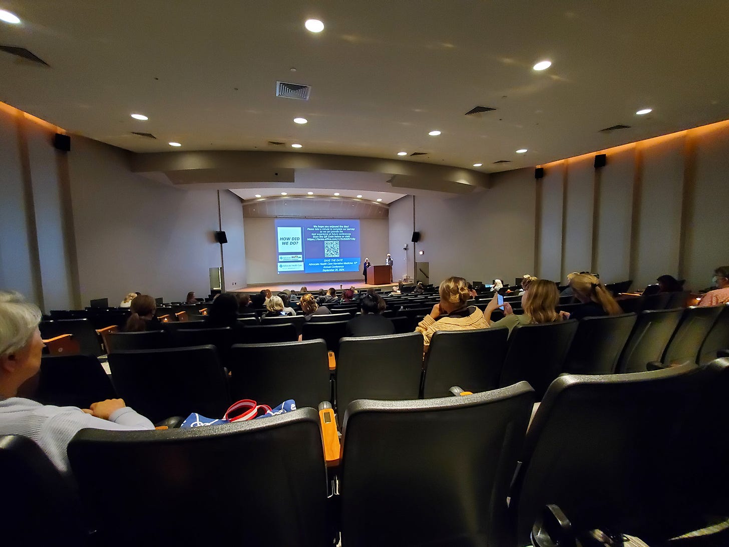 an auditorium with seats and a presentation on the screen