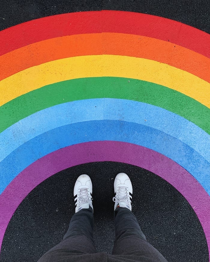 A painted rainbow around a pair of shoes. You view it from the perspective of the person wearing the shoes. A painted rainbow around a pair of shoes. You view it from the perspective of the person wearing the shoes.