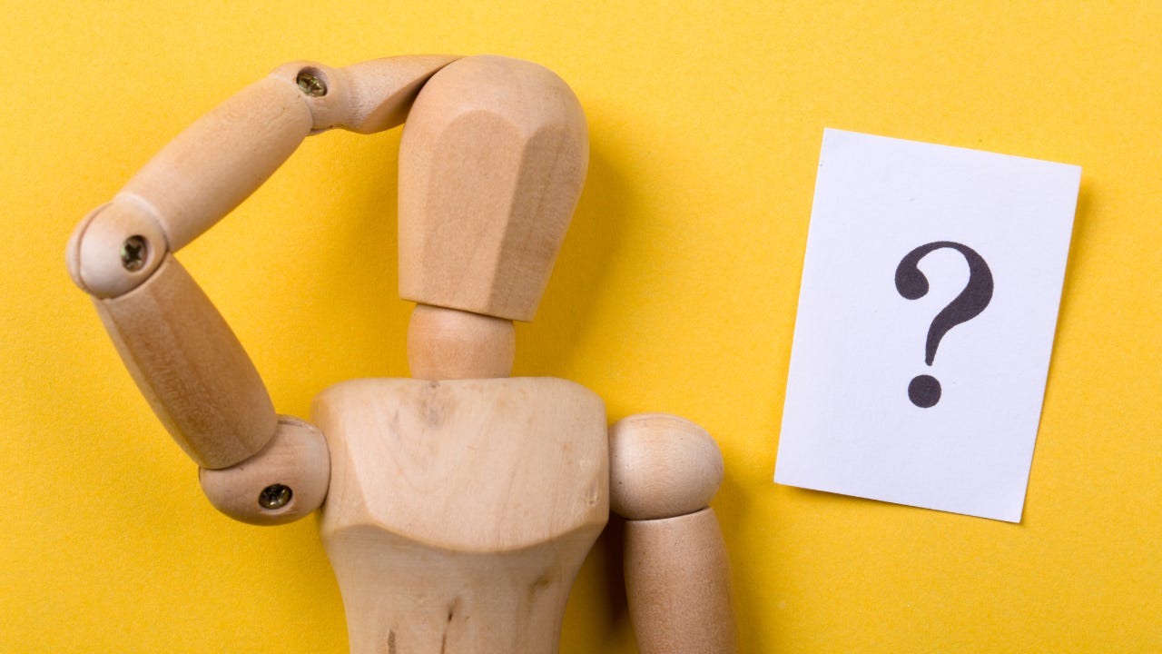 A wooden person thinking next to a question mark.
