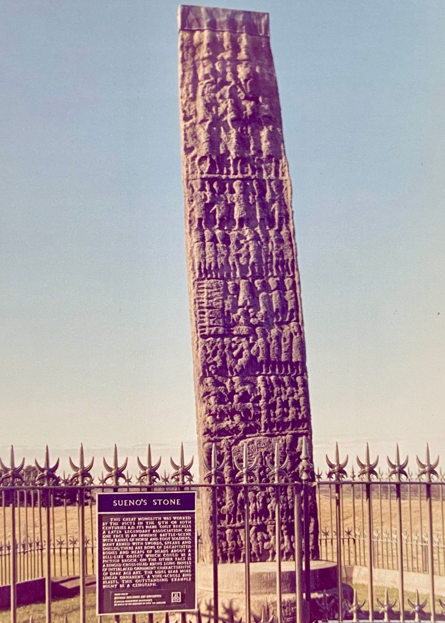Photo of Sueno’s Stone near Forres, taken in the 1980s by Ronnie Nielson. Photo shows the east face of the stone with its tiers of battle scenes.