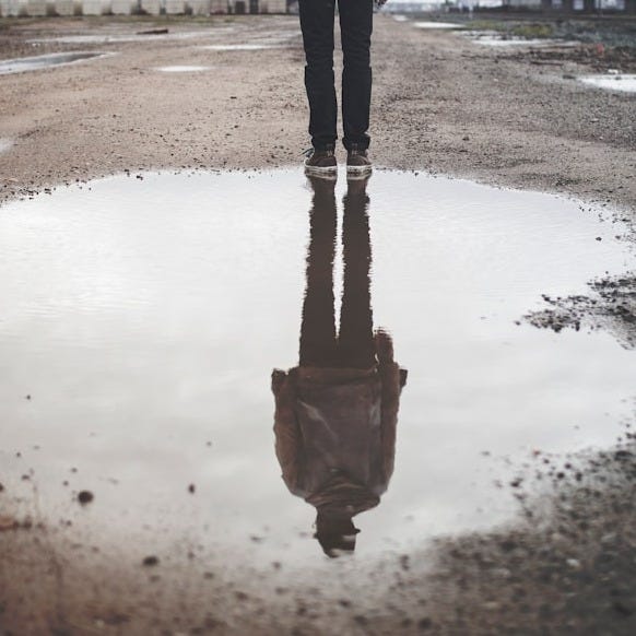 man's reflection on body of water photography