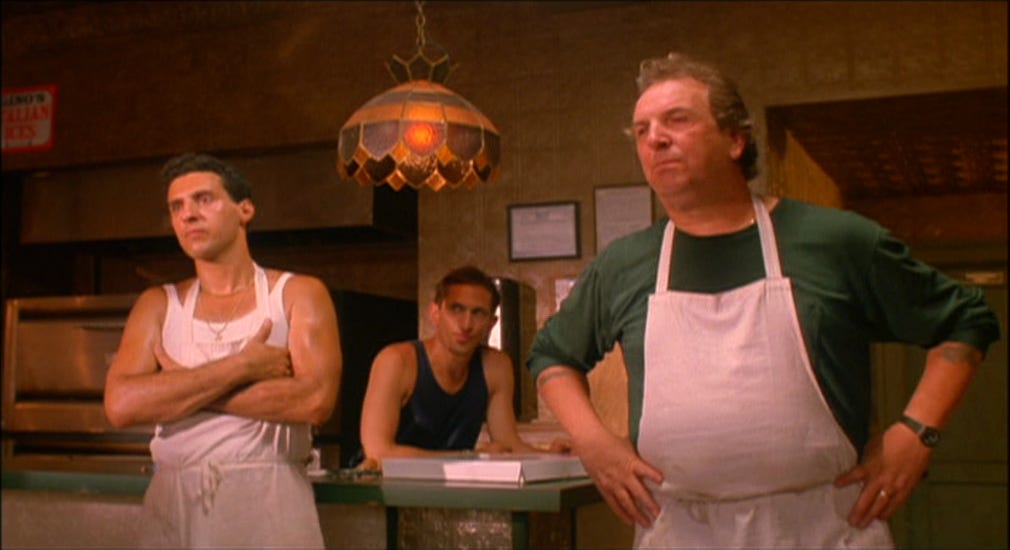 This image shows the Frangione family from Spike Lee's 1989 film Do the Right Thing standing next to the counter of Sal's Famous Pizzeria. Left to Right: Pino Frangione (played by John Turturro), Vito Frangione (played by Richard Edson), & Sal Frangione (played by Danny Aiello).