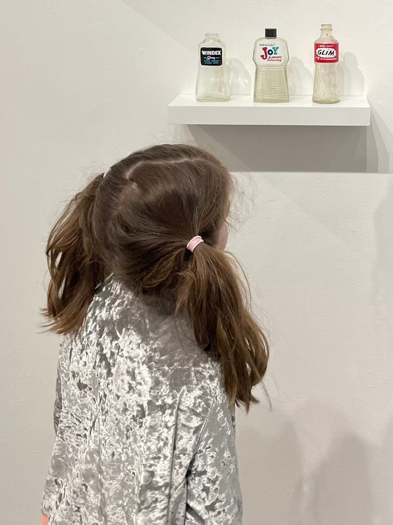 girl looking at old bottles ata gallery show girl looking at old bottles ata gallery show