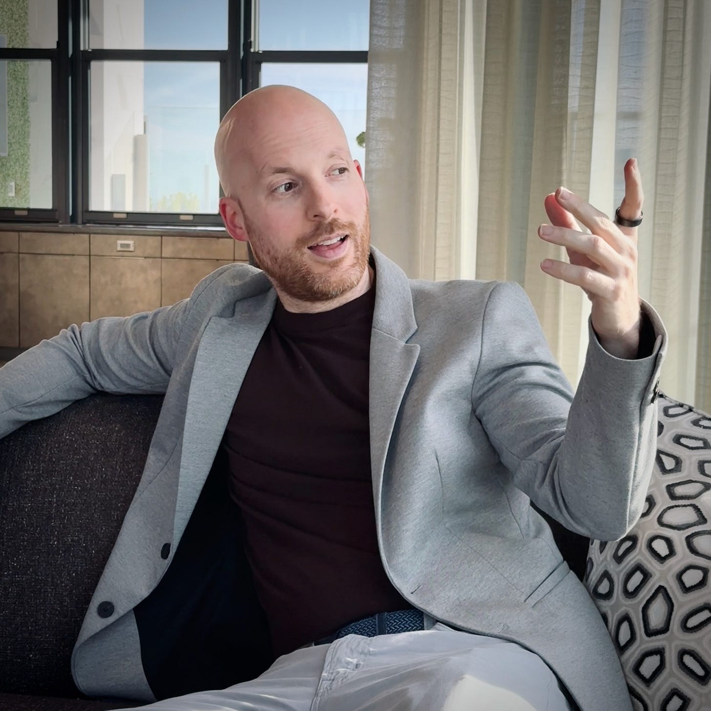 Oliver Emberton in a suit, sat on a sofa