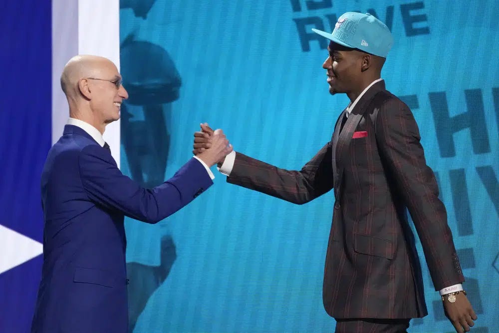 Brandon Miller, right, greets NBA Commissioner Adam Silver after being selected second overall by the Charlotte Hornets during the NBA basketball draft, Thursday, June 22, 2023, in New York. (AP Photo/John Minchillo)