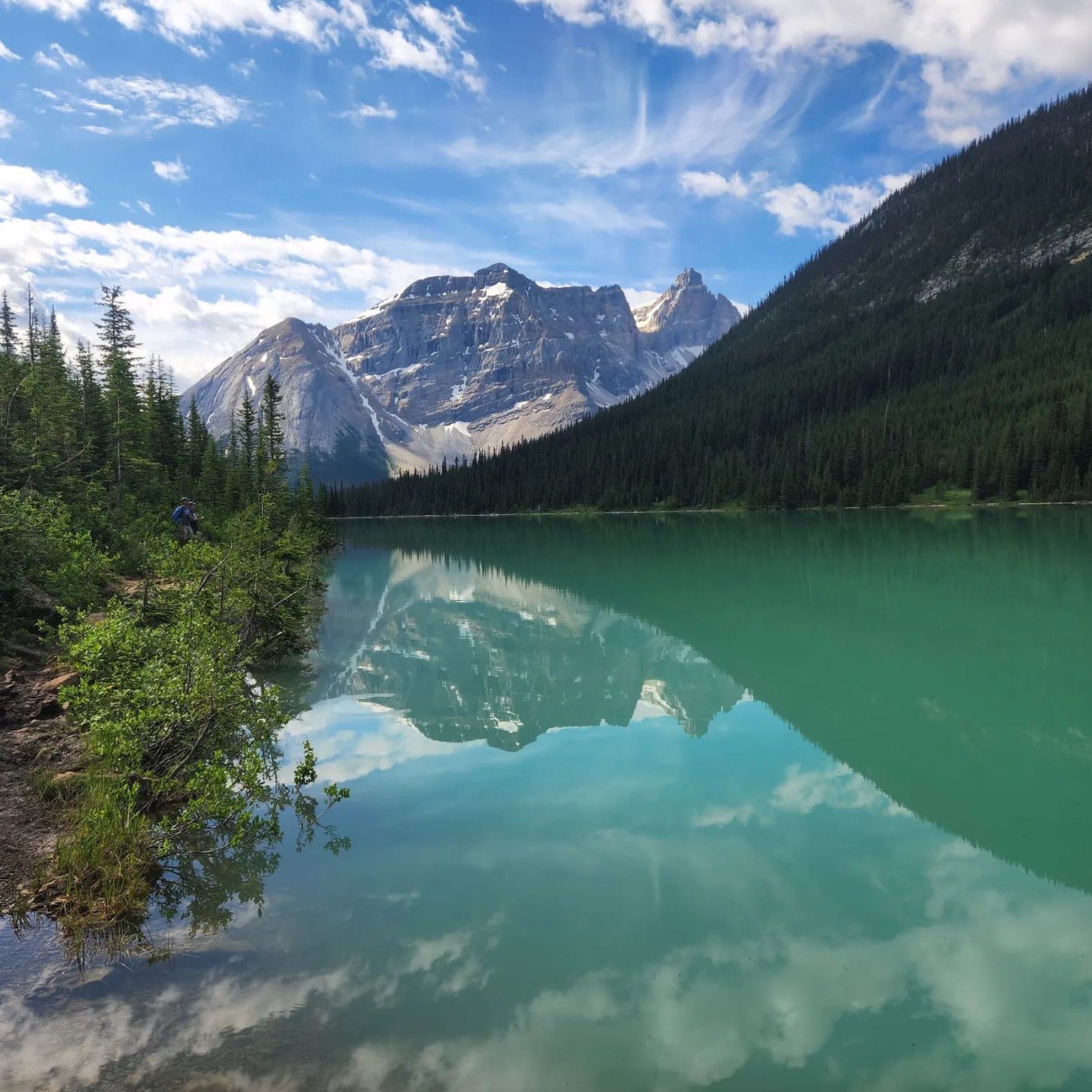 View of sky and mountains reflecting in an ice blue glacial lake in Banff