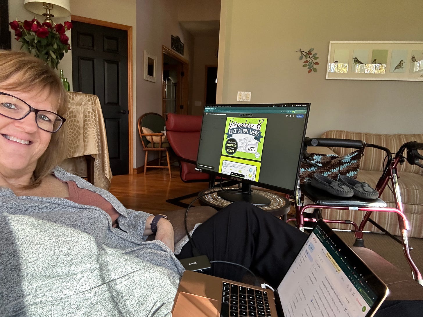 The author with laptop and additional monitor, in recliner with rolling walking in the background.