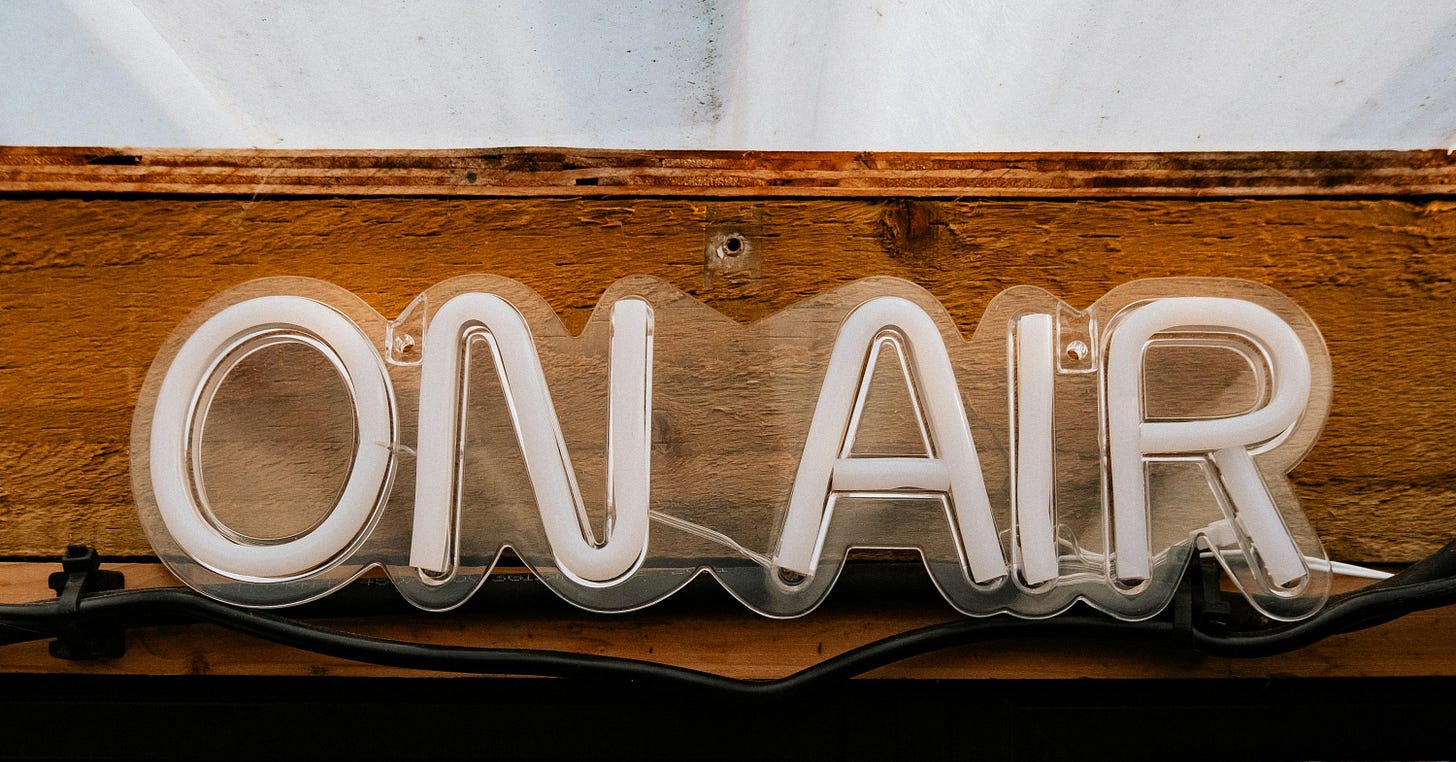 a wooden sign that says on air above a crowd of people