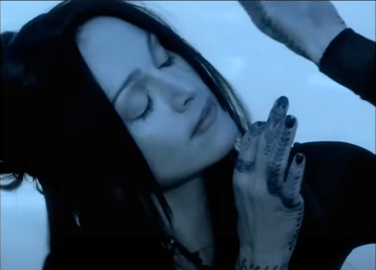 Madonna with her eyes closed in close-up posing with her hands near her face in the Frozen video