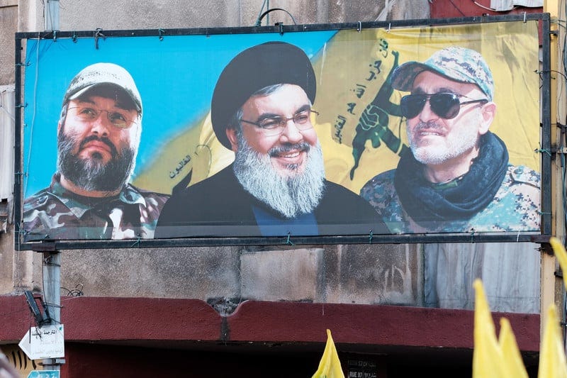 A billboard shows Nasrallah with two comrades 