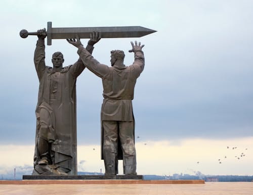 Free Imposing statue of two heroic figures holding a sword, symbolizing strength and unity. Stock Photo