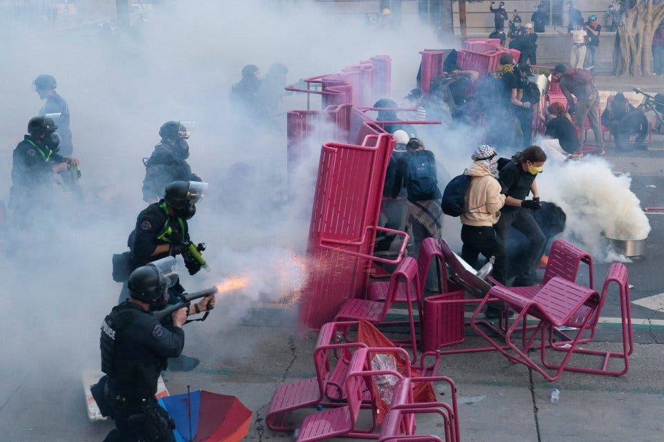 Police using tear gas to disperse demonstrators blocking a street.