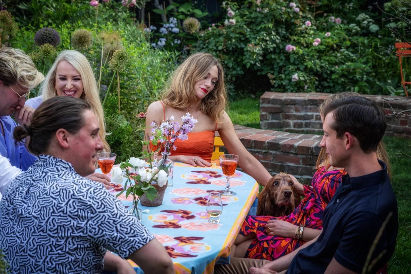 A group of people sitting around a table with a dog

Description automatically generated
