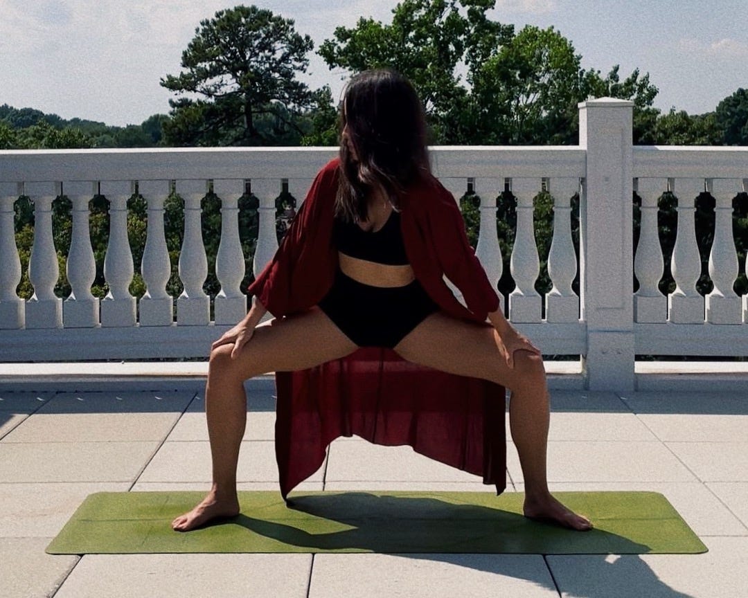 Woman practicing yoga on a rooftop with a green yoga mat