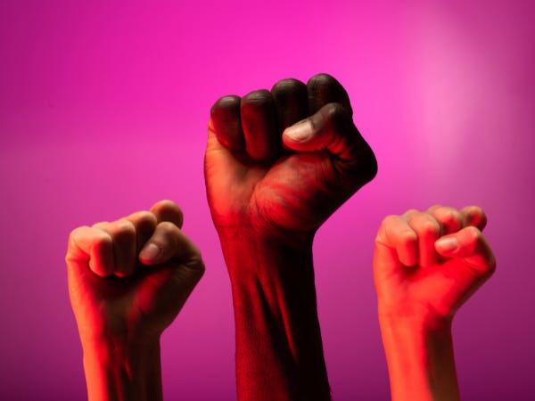 3 clenched fists in the air against a hot pink background