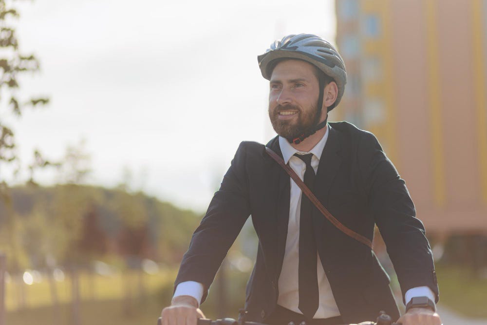 Photo happy bearded businessman in protective helmet commuting to work.