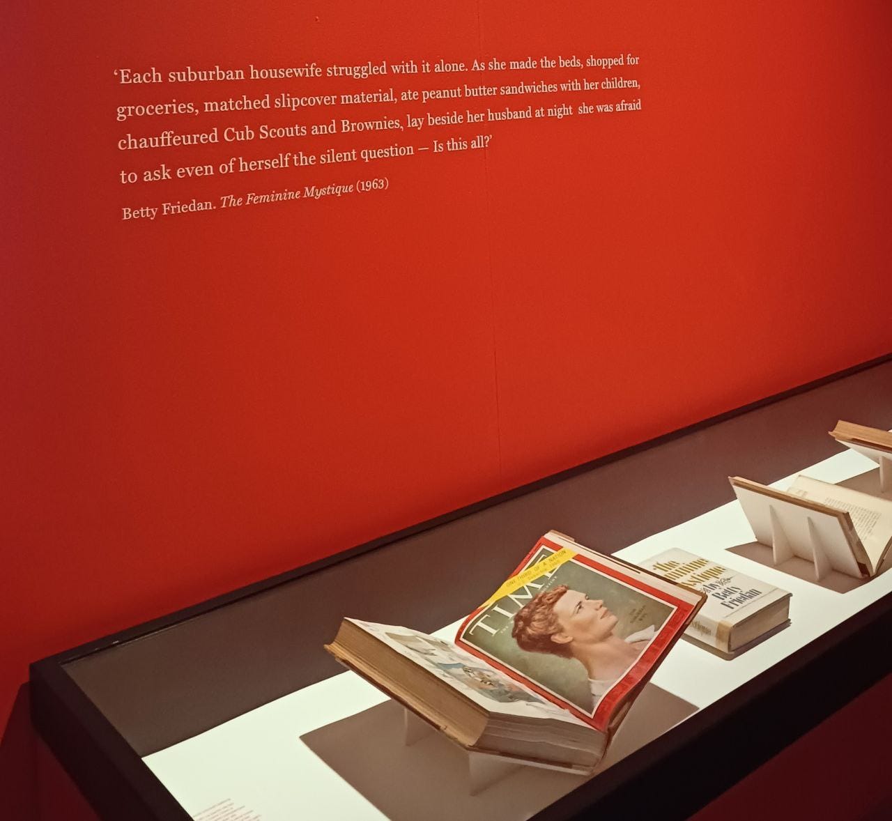 La parete rossa del CCCB di Barcellona dove campeggia la frase di Betty Friedan tratta da The Feminine Mystique: Each suburban wife struggles with it alone. As she made the beds, shopped for groceries, matched slipcover material, ate peanut butter sandwiches with her children, chauffeured Cub Scouts and Brownies, lay beside her husband at night- she was afraid to ask even of herself the silent question - 'Is this all?