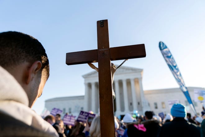 An anti-abortion protester holds a cross in front of the Supreme Court in 2021.