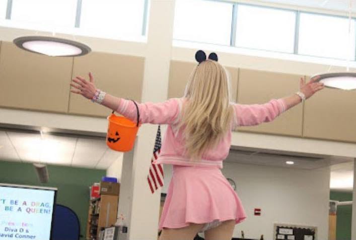 Drag Queen with pink miniskirt stands on a table