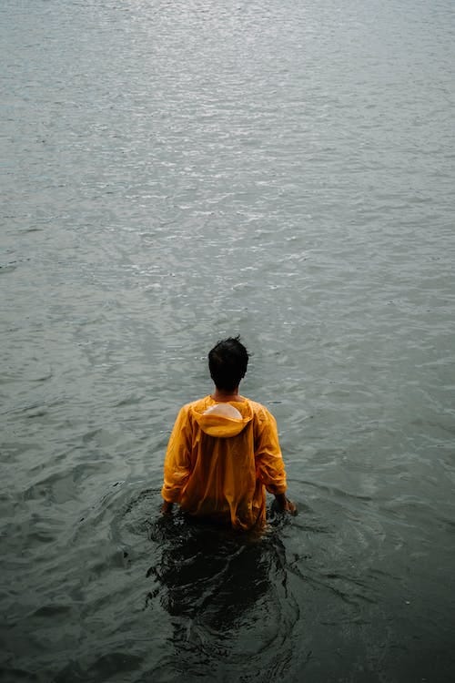 Free Back View of Man Wearing Yellow Hoodie Standing in the Water Stock Photo