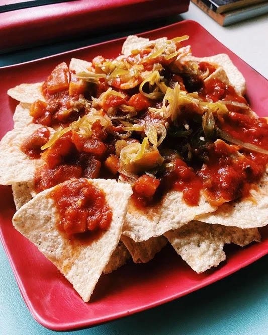 A plate of nachos and salsa from The Nacho King