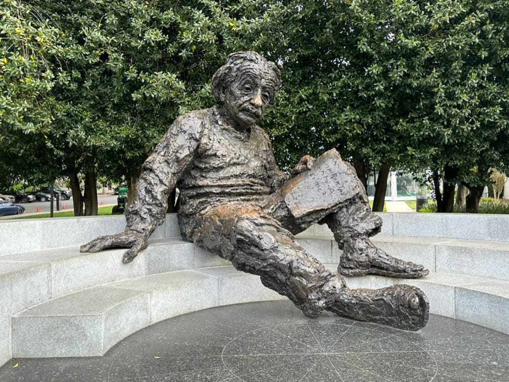 A statue of a person sitting on a stone ledge

Description automatically generated