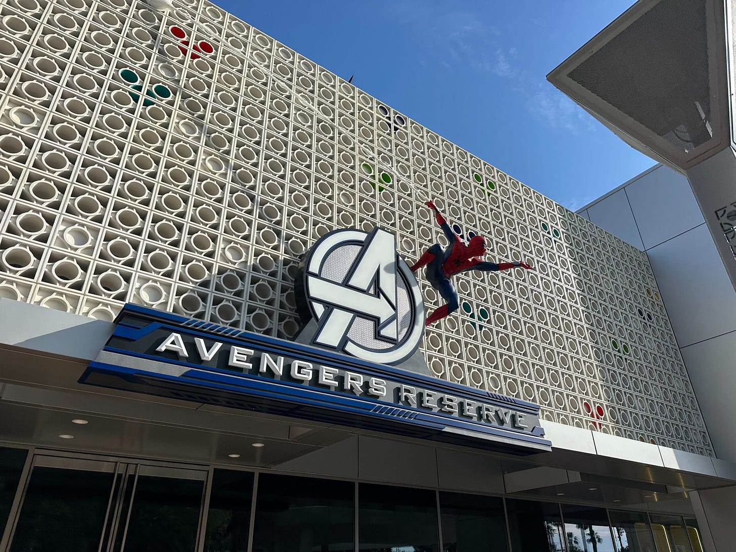 Building facade with an Avengers logo and a Spider-Man figure climbing above a sign that reads "Avengers Reserve.