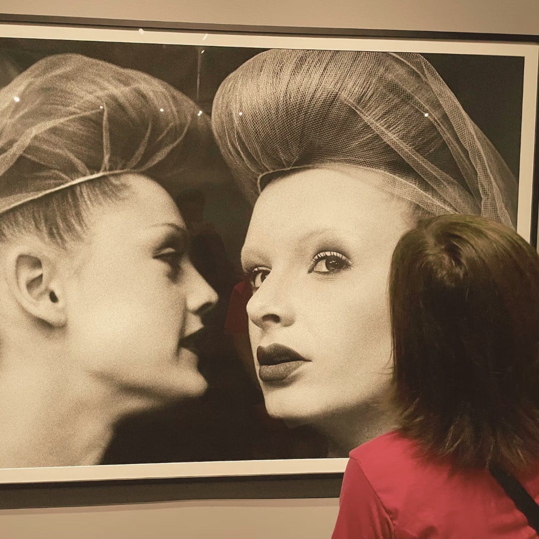 A photograph of Sarah looking closely at a large photograph, hanging in an art gallery.