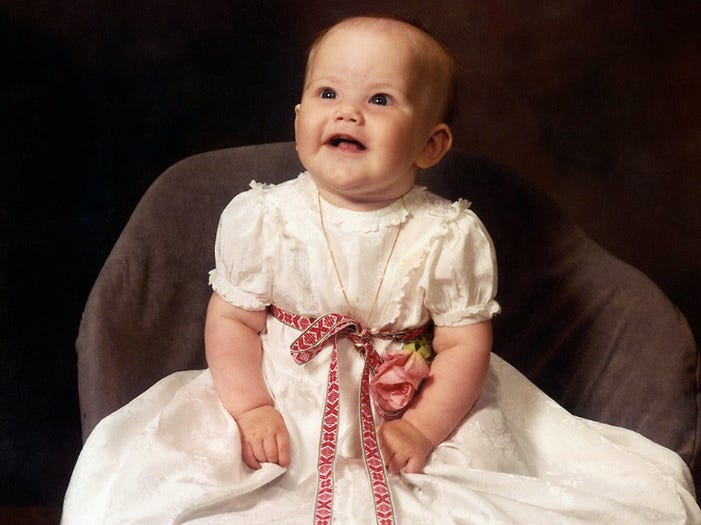 Princess Sofia of Sweden as a baby wearing a white dress and red ribbon