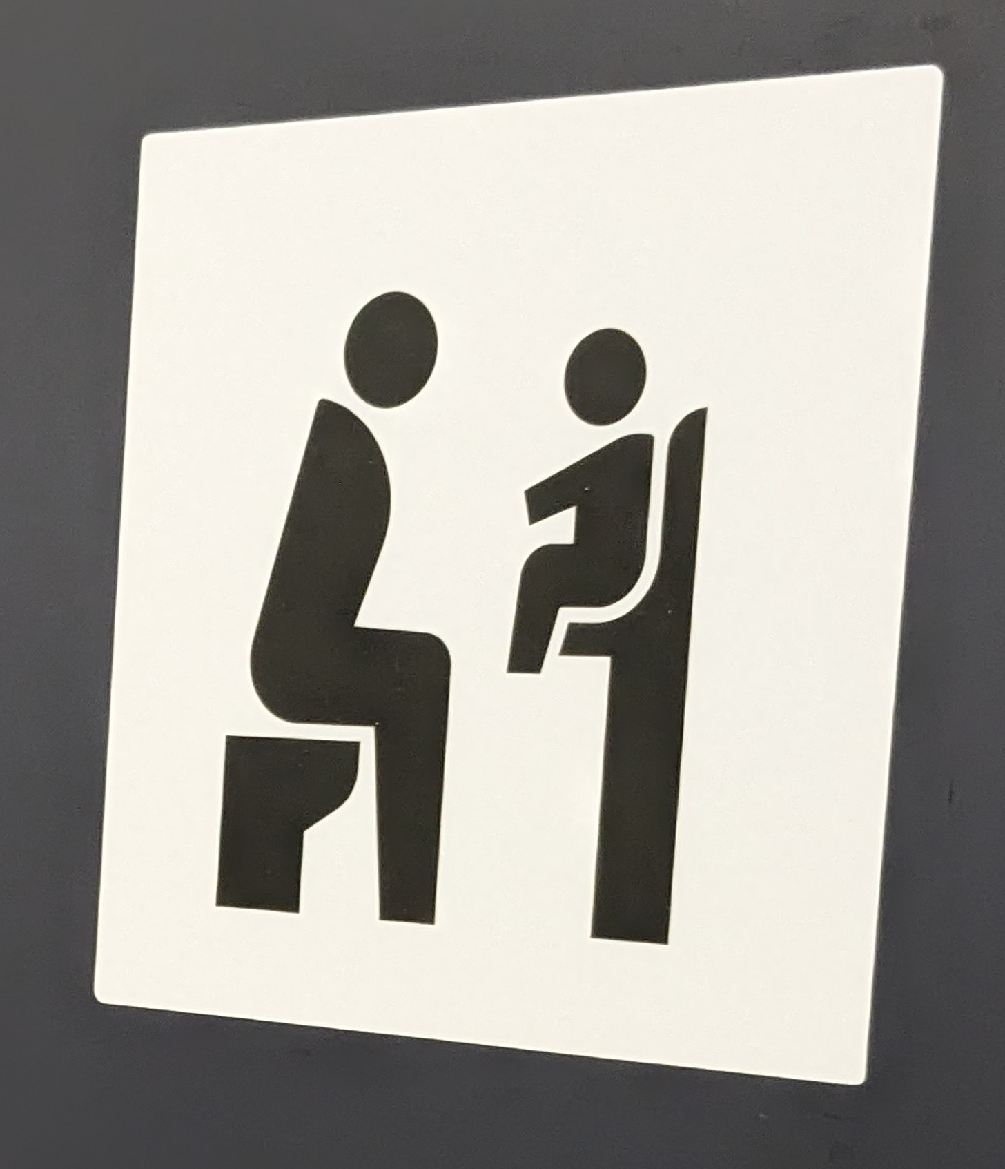 Graphic of a parent seated on a toilet facing a toddler seated on a wall-mounted toddler seat