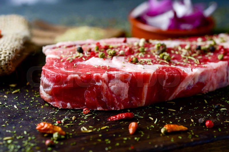 Closeup of a raw strip steak seasoned with different spices, | Colourbox
