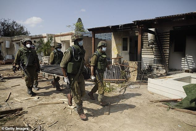 Israeli soldiers remove the body of a civilian, who was killed days earlier in an attack by Hamas on this kibbutz Kfar Aza near the border with Gaza