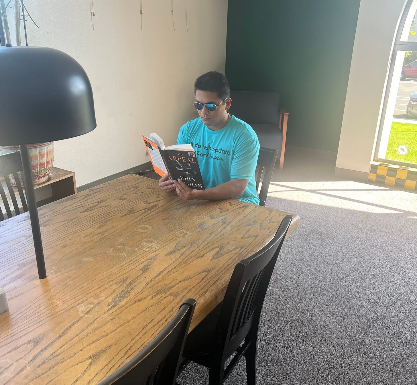 A person sitting at a table reading a book

Description automatically generated