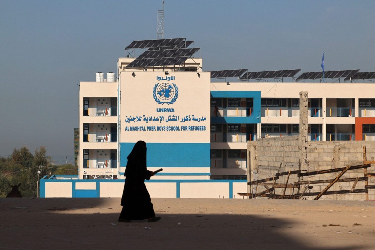 A Palestinian woman walks past the shuttered headquarters of the United Nations Relief and Works Agency for Refugees (UNRWA) in Gaza City [MOHAMMED ABED/AFP via Getty Images]