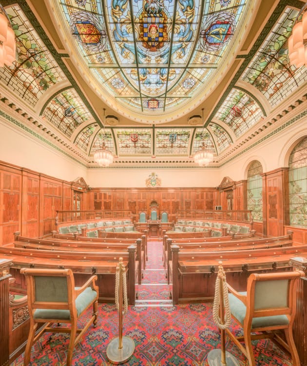 Free Interior of a historic council chamber in Halifax, England featuring stained glass ceiling and ornate wooden details. Stock Photo