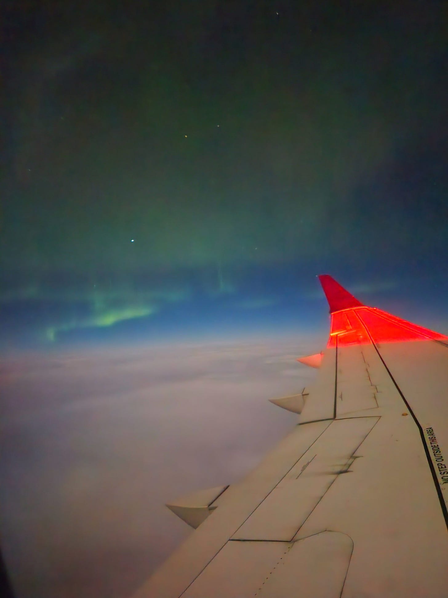faint green aurora over the wing of an airplane