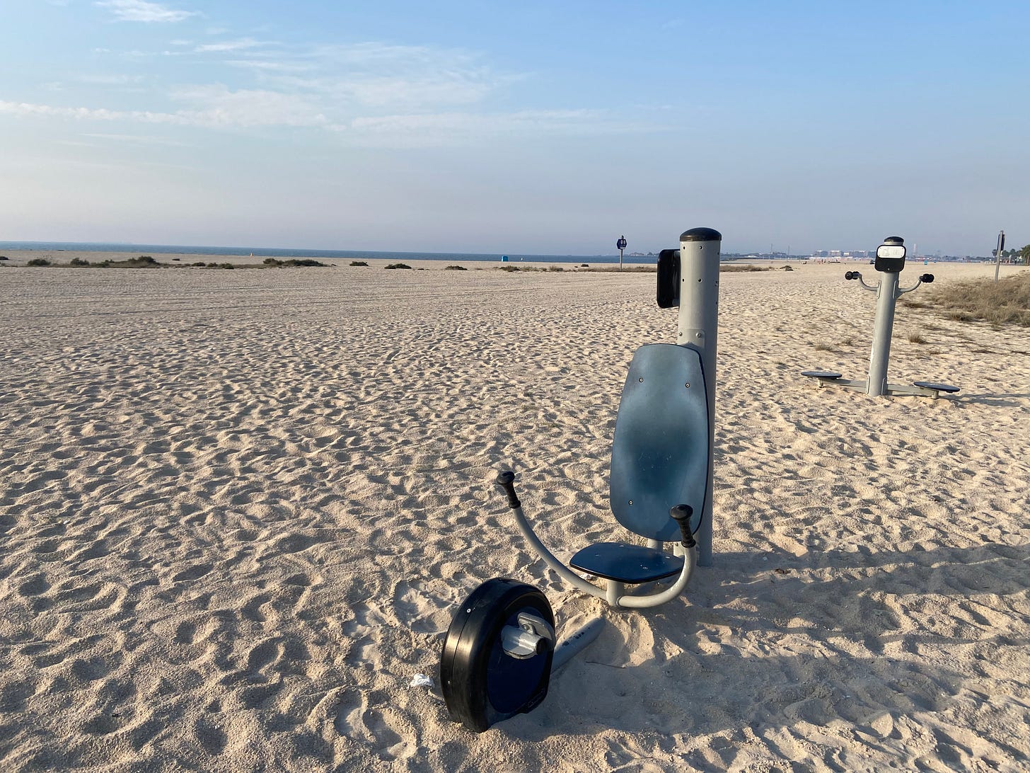 Photo of a sandy beach during late afternoon hours with a pair of non-electric gym equipment on the sand