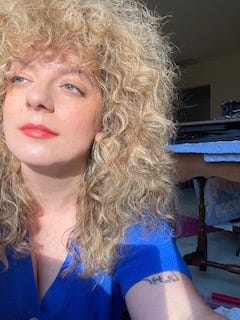 Woman with blonde curly hair a la Stevie Nicks or something and a blue shirt