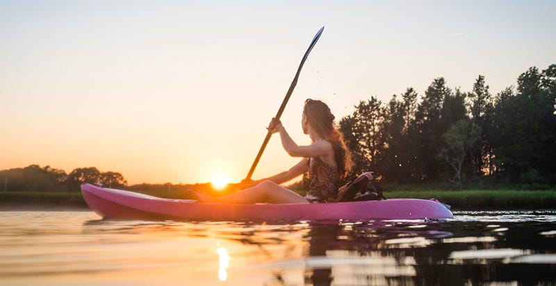 A woman kayaking as the sun sets