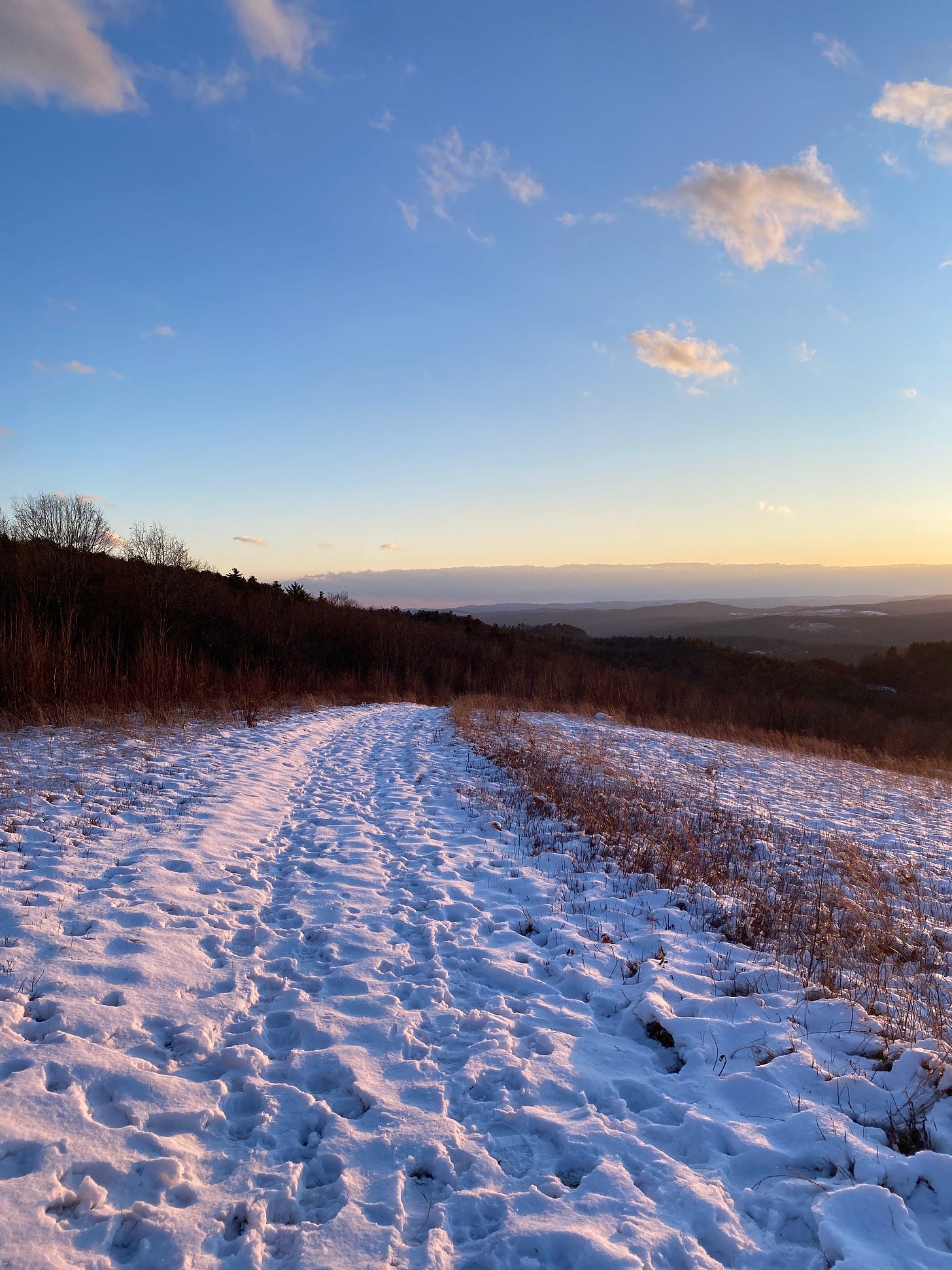 A sunny, snowy path along a ridgetop.