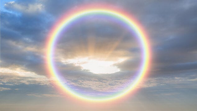 A rainbow circle in the middle of a cloudy sky.
