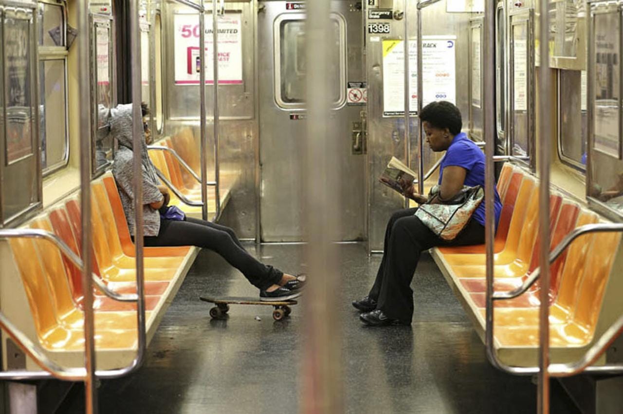 A woman reads a book on the #3 subway train.