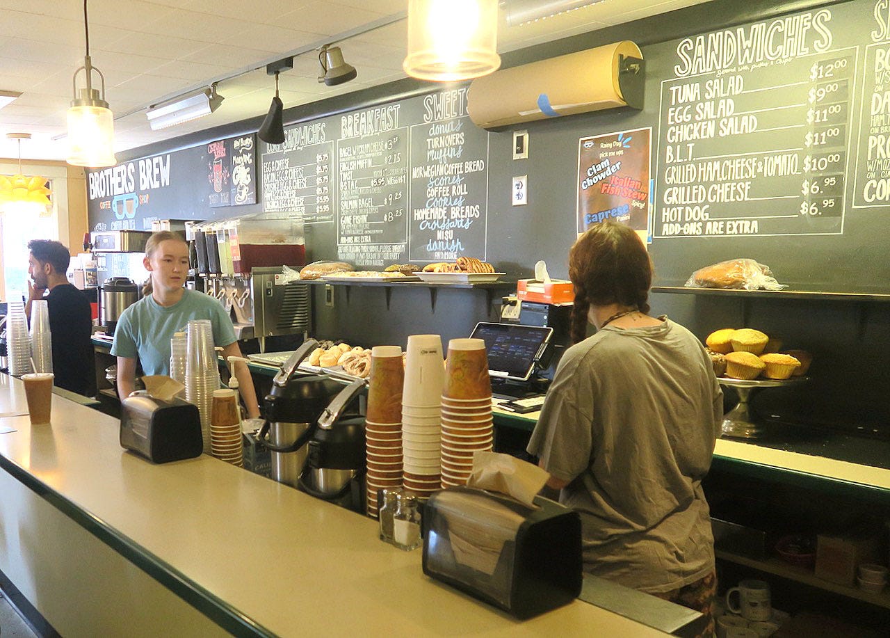 A person behind a counter in a coffee shop

Description automatically generated