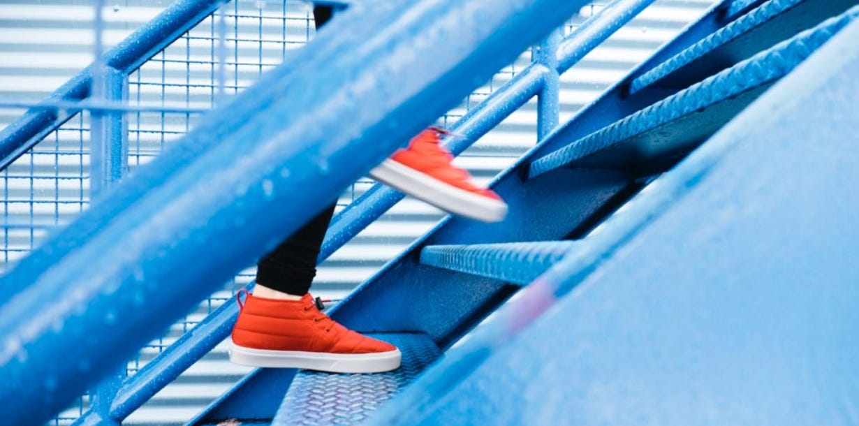 person in orange shoes walking up blue metal stairs