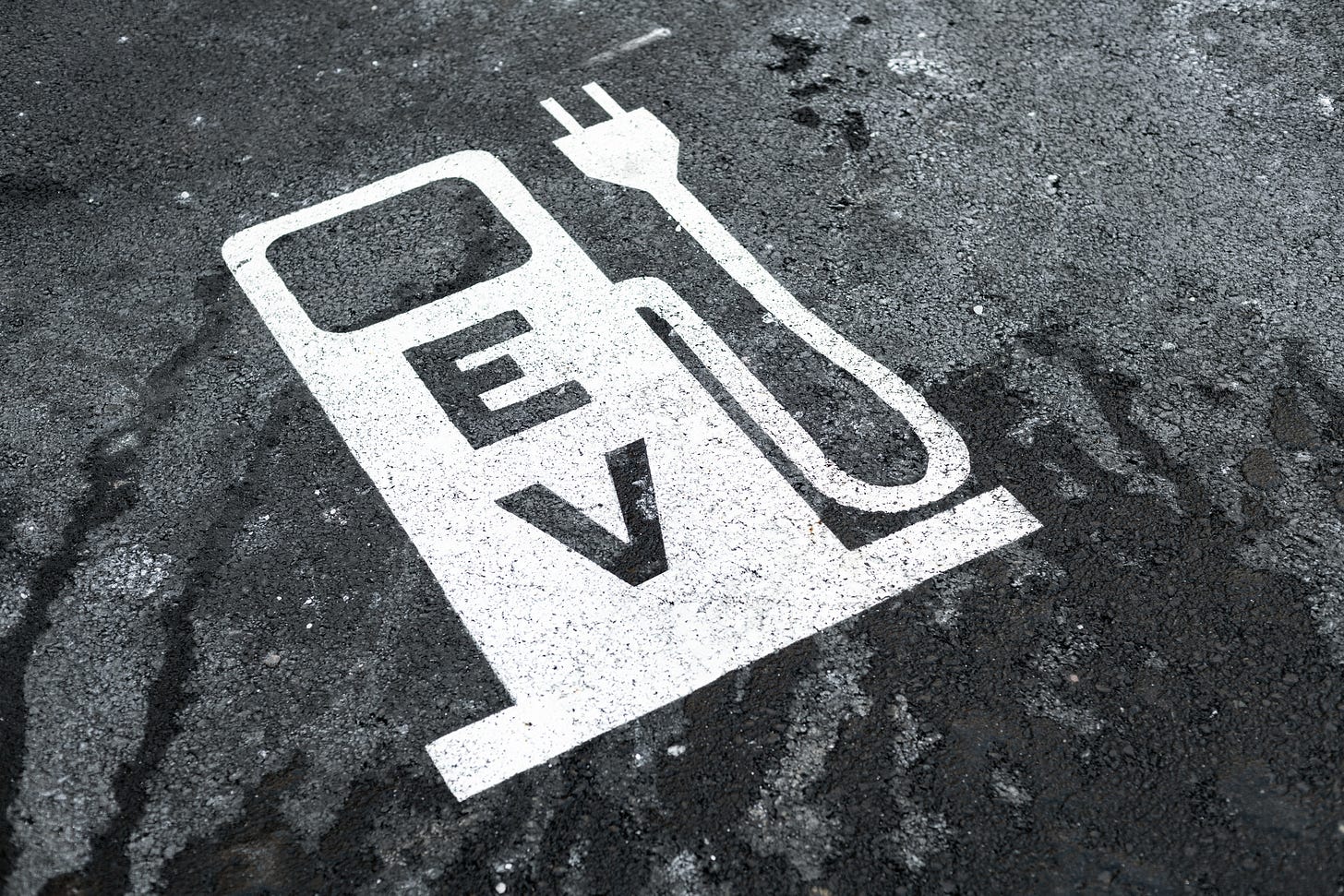An electric vehicle logo printed on asphalt.