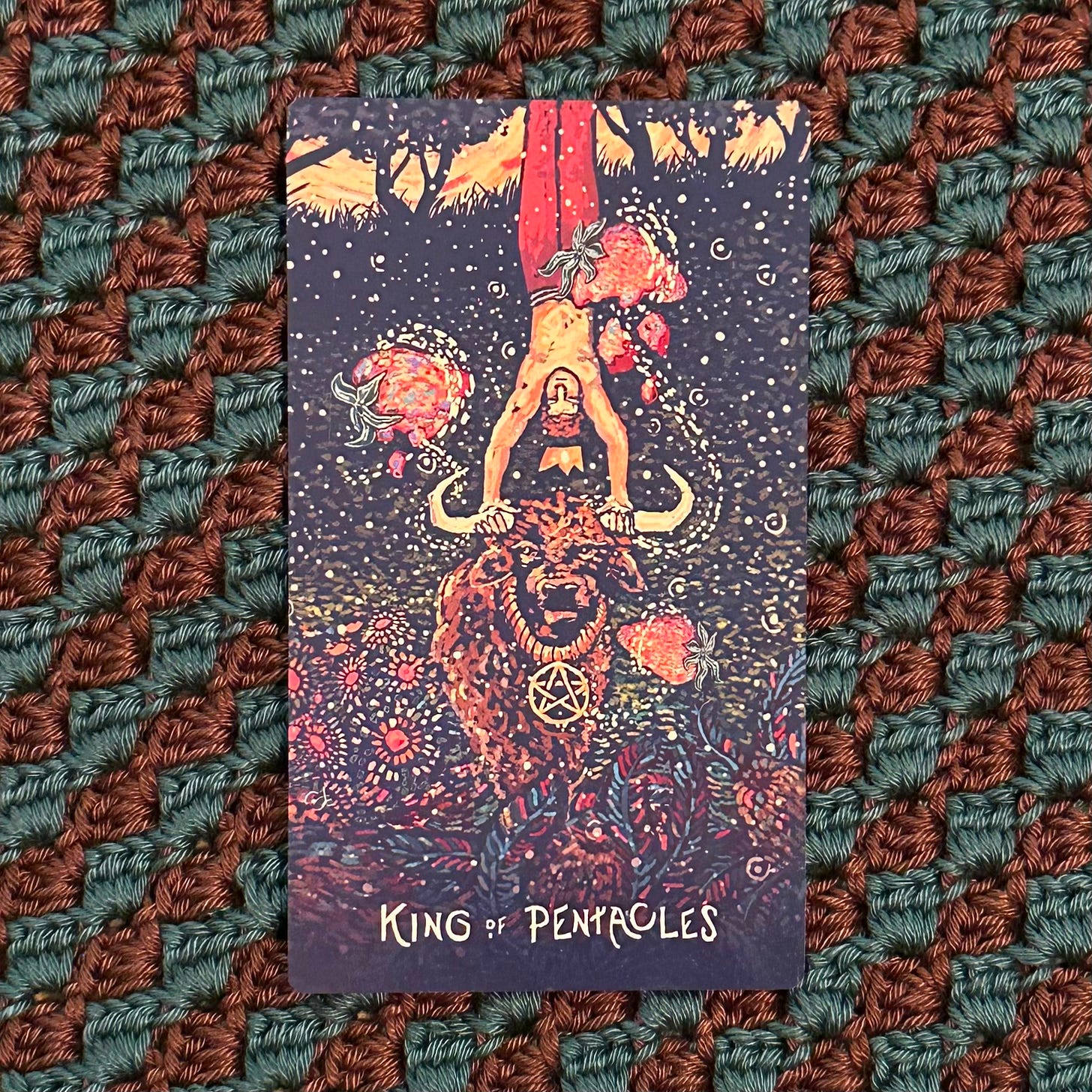 Prisma Visions tarot card "King of Pentacles" showing a man doing a handstand on a bulls horns