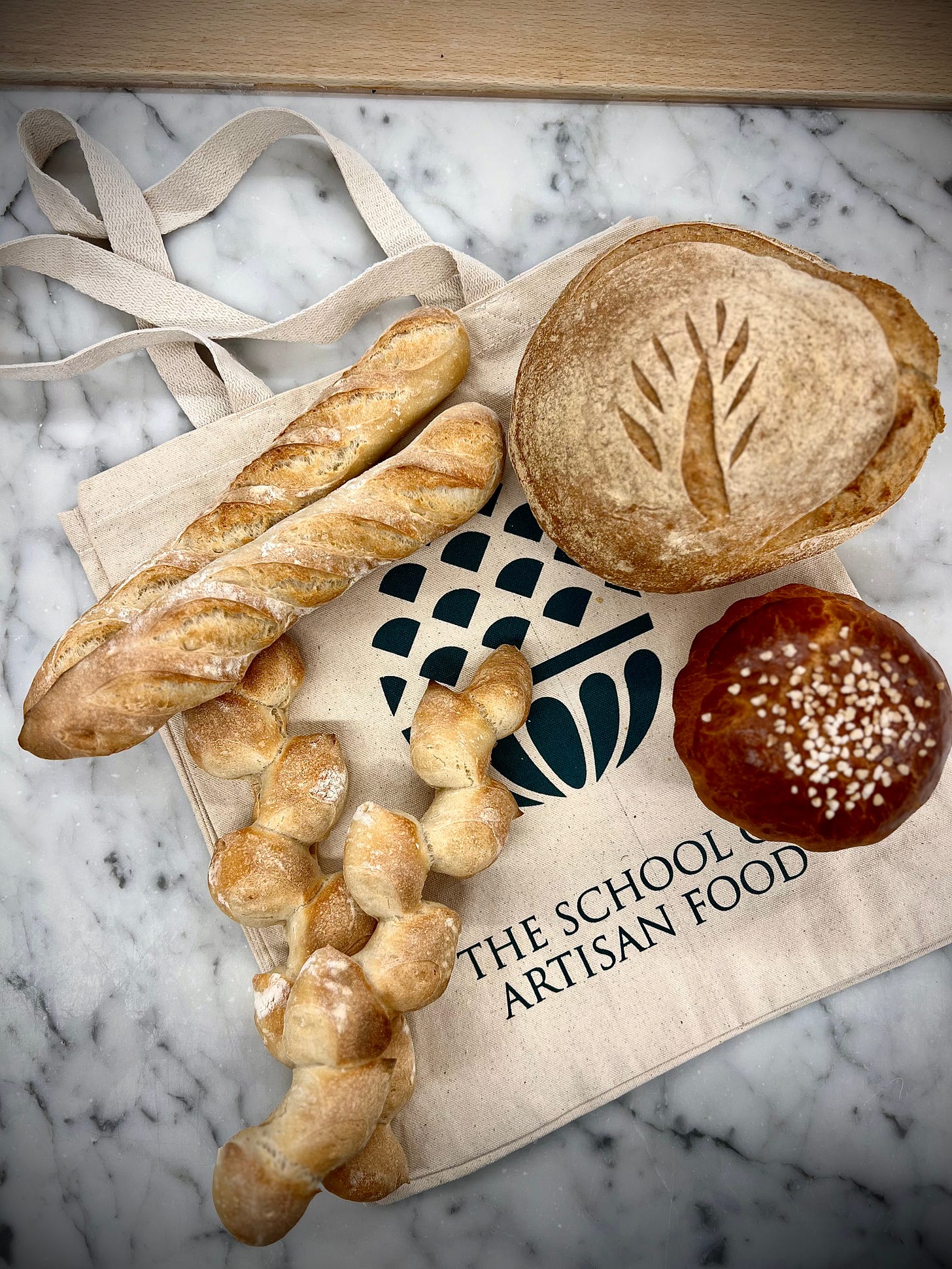 selection of bread sitting on a School of Artisan Food bag